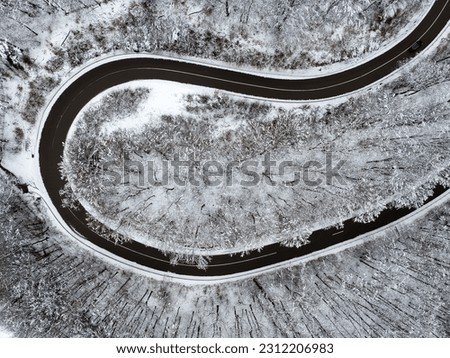 Curving winter roads from a bird eye view. This road is in a forest. Amazing snowy landscape from above