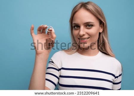 close-up photo of joyful happy young woman showing off buying real estate holding keychain of keys on blue isolated background