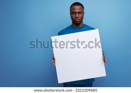 young handsome american man in a t-shirt tells the news on a billboard on the background with copy space