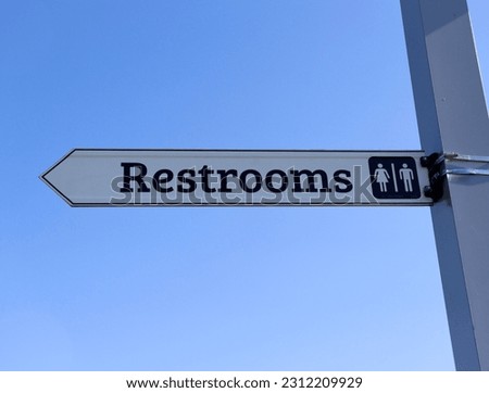 A close view of the restroom sign on the pole.
