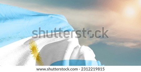 Argentina national flag cloth fabric waving on beautiful grey sky Background.