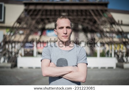 Young stylish guy on a eiffel tower background, the sun shines