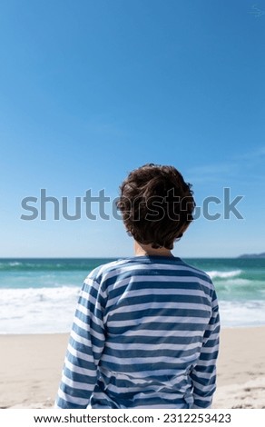 Rear view of a boy looking to the sea, vertical image