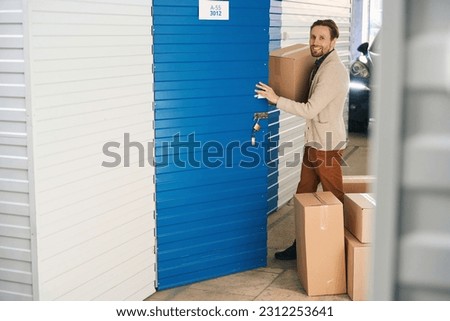 Young man with big cardboard boxes in self storage unit Royalty-Free Stock Photo #2312253641
