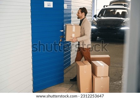 Side view of man with big cardboard boxes in self storage unit Royalty-Free Stock Photo #2312253647