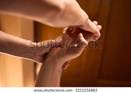 Qualified practitioner giving hand massage to spa salon client