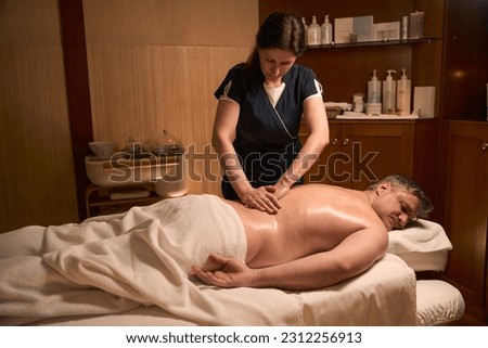 Specialist adjusting patient vertebral column during manual therapy session Royalty-Free Stock Photo #2312256913