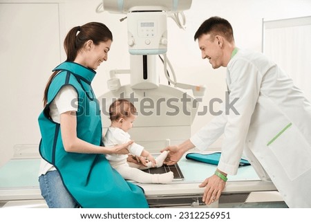 Friendly radiologist preparing child for radiography of lower limb Royalty-Free Stock Photo #2312256951
