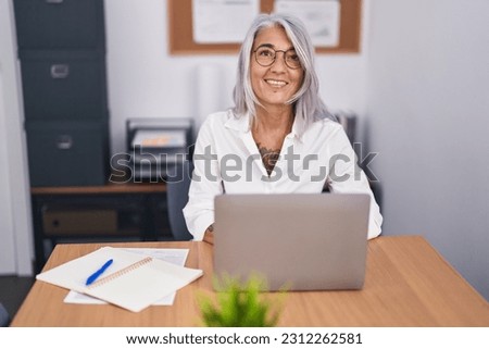 Middle age grey-haired woman business worker using laptop working at office