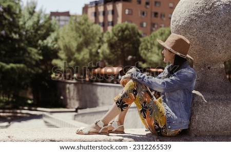 Young tourist sitting on bridge relaxing on summer afternoon