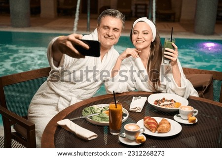 Cheerful couple photographing themselves at lunch in wellness center