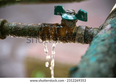 Water leakage at the junction of the water shut-off valve and pipe. Technical problem of rusty pipes in the garden. Royalty-Free Stock Photo #2312269353