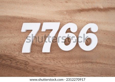 White number 7766 on a brown and light brown wooden background.