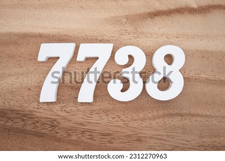 White number 7738 on a brown and light brown wooden background.