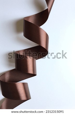 Beautiful curls of a wide brown satin ribbon on a white background