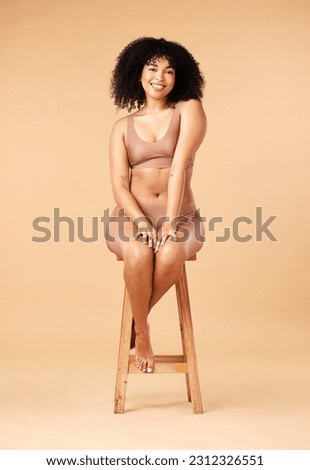 Body positive, beauty and black woman sitting on a chair for skincare and self care isolated in a studio brown background. Plus size, portrait and natural model smile, happy and glow due to cosmetic