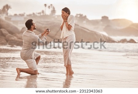 Couple at beach, surprise proposal and engagement with love and commitment with ocean and people outdoor. Travel, seaside and man propose marriage to woman, wow reaction and happiness with care Royalty-Free Stock Photo #2312343363