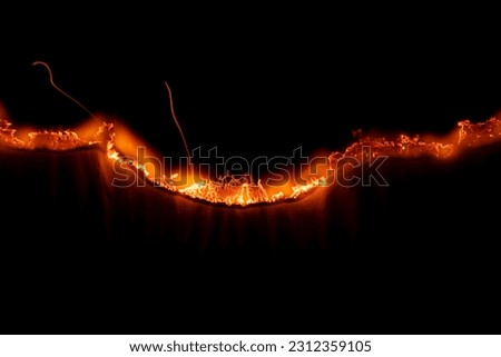 burning paper, glowing edge of paper on a black background Royalty-Free Stock Photo #2312359105
