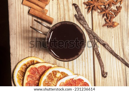Glogg glass, near vanilla, cinnamon sticks and star anis. On wooden background