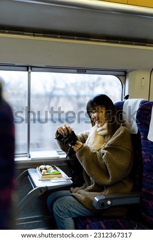 Asian woman using digital camera taking picture of traditional Japanese lunch box bento during travel on train. Attractive girl travel Japan on railroad transportation on winter holiday vacation.