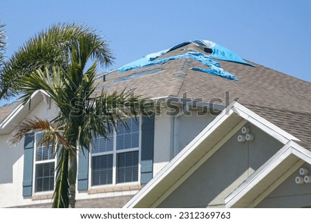 Destroyed Tarp on the roof waiting to get repaired Royalty-Free Stock Photo #2312369763