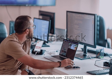 A programmer diligently testing smartphone applications while sitting in their office. Royalty-Free Stock Photo #2312374465