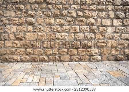 Background with an ancient brick wall and pavement of old city of Jerusalem, Israel Royalty-Free Stock Photo #2312390539