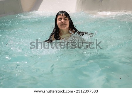 portrait of smiling girl with long hair swimming in water after water slide Royalty-Free Stock Photo #2312397383