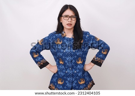 Angry Asian female in batik korpri, indonesian traditional uniform standing with hands on waist Royalty-Free Stock Photo #2312404105