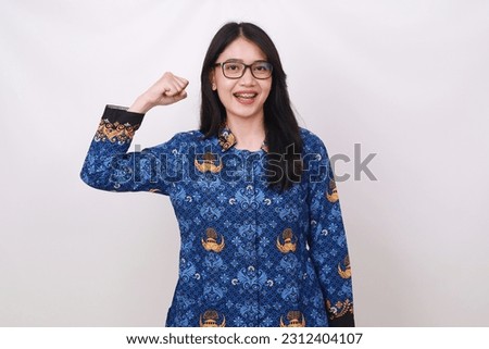 Asian female in batik korpri, indonesian traditional uniform making strong gesture with fist hand Royalty-Free Stock Photo #2312404107