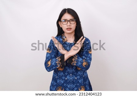 Asian female in batik korpri, indonesian traditional uniform crossing her hands Royalty-Free Stock Photo #2312404123