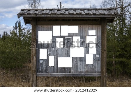 Old wooden bulletin board outdoors with empty white notes. Royalty-Free Stock Photo #2312412029