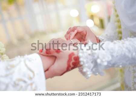 Put on the wedding ring. Precious metal jewelery for married couple. Ceremony and wedding planning. Holding traditional bridal commitment jewelery. Gold rings for muslim brides in indonesia Royalty-Free Stock Photo #2312417173