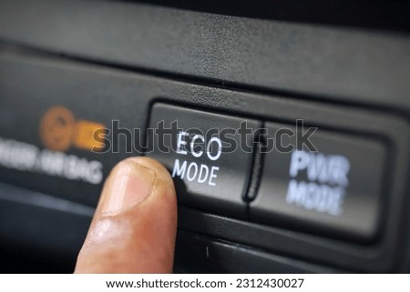 car driver pressing eco mode button on luxury car dashboard.  eco mode is a relaxed and fuel efficient driving mode Royalty-Free Stock Photo #2312430027