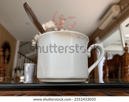 This is a photo of a cup of coffee in the morning with a blurred background. 