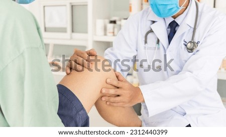 The orthopedic doctor or surgeon in white gown examined the patient with knee pain problem.White clean table or bed with blur background.Knee ligament or meniscus sport injury.Orthopaedic unit. Royalty-Free Stock Photo #2312440399