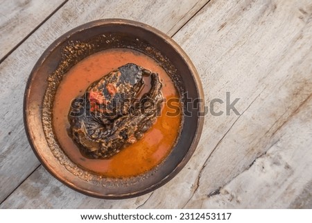 Top view photo of Mangut Lele typical Javanese food from Yogyakarta and Solo. Traditional catfish dishes are full of spices and spicy in earthenware plate on wooden table.