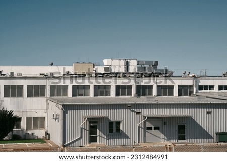 modern industrial warehouse exterior. The warehouse is a large, purpose-built building designed for industrial purposes.  Its architecture features a clean and contemporary design. Royalty-Free Stock Photo #2312484991