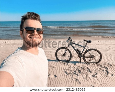 Man with the bike on the sea making selfie