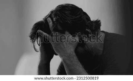 Dramatic depressed young man suffering from emotional pain. Somber closeup face of a male person in 30s feeling sadness and lost in monochromatic black and white Royalty-Free Stock Photo #2312500819