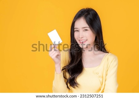 Asian woman cute girl holding and showing empty business card or name card - for payment shopping online and - paying by credit card isolated on yellow - business concept