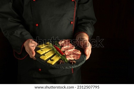Professional chef is holding a serving plate with an appetizer of ham and cheese. The concept of serving food by the waiter. Free space for recipe or menu on black background