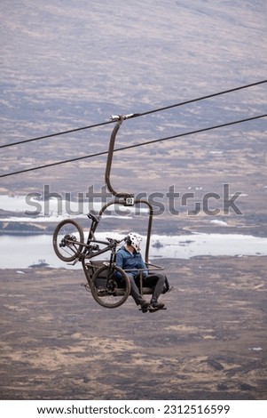 Mountain bicycle and extreme sports cyclist on a ski lift going up to a moutain sports resorts in Scotland
