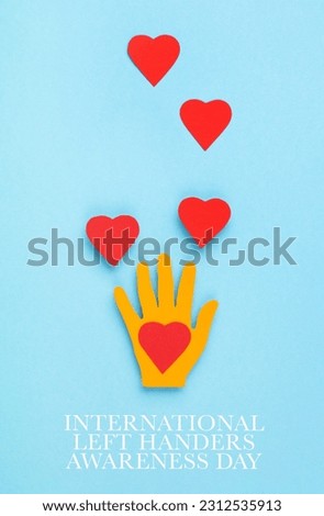 International Left Handers Day Concept, 13th august. Colorful paper left hand and red hearts on blue background, copy space, top view. Royalty-Free Stock Photo #2312535913