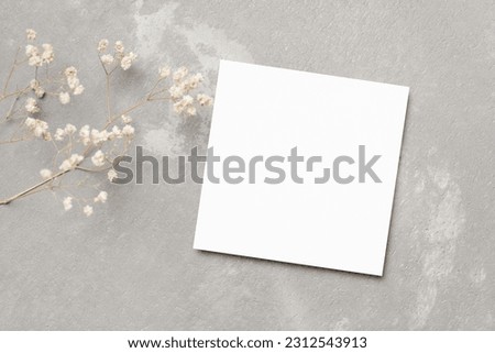 Blank square card mockup with dry flowers on grey background, greeting or invitation card mockup flat lay