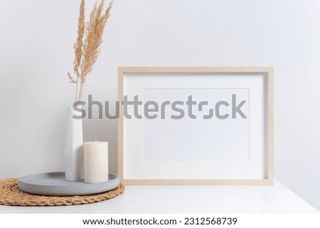 Horizontal picture frame mockup in white room with interior decorations, blank wooden frame mock up