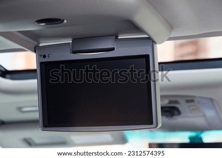 Entertainment system for rear passengers in a car with monitor mounted on the ceiling for watching TV, cartoons and computer games. Royalty-Free Stock Photo #2312574395