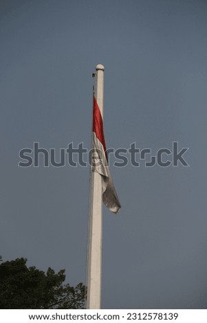Indonesian flag against a blue sky background.