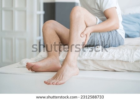 The man's calf muscle cramped, massage of male leg at home, painful area highlighted in red Royalty-Free Stock Photo #2312588733