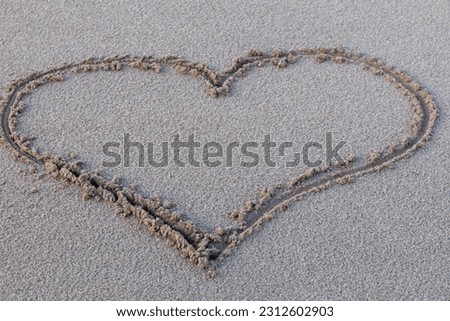 A heart drawn in the sand by the coast